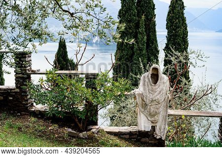 Ghost Statue On A Stone Fence Among Green Trees On The Shores Of Lake Como. Italy