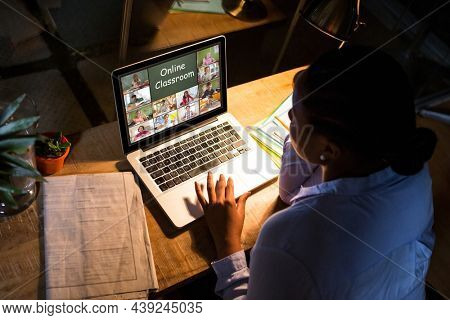 African american woman using laptop for video call, with diverse elementary school pupils on screen. communication technology and online education, digital composite image.