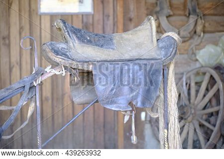 Old Horse Saddle Hanging In A Wooden Shed.