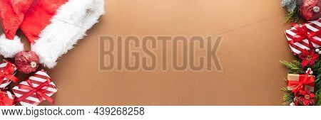 Christmasbanner With Gift Boxes, Santa Hat And Winter Decorations On Brown Background, Top View. Cop