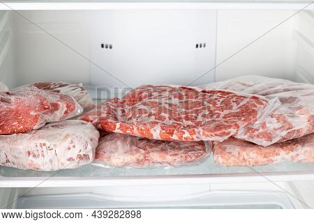 Frozen Raw Meat Wrapped Plastic In The Freezer. Frozen Food