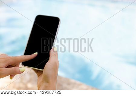 Female Hand Holding Smartphone And Typing With Index Finger Near Swimming Pool.