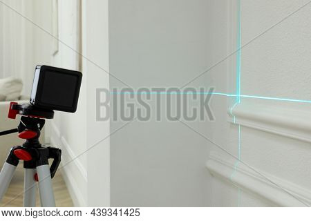 Cross Line Laser Level On Tripod In Front Of White Wall