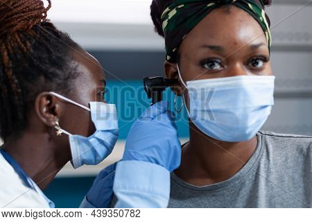 Closeup Of African American Otologist Doctor Looking At Ear Of Sick Patient Using Medical Otoscope D