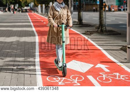 traffic, city transport and people concept - happy smiling woman riding electric scooter along red bike lane with signs of bicycles and two way arrows on street