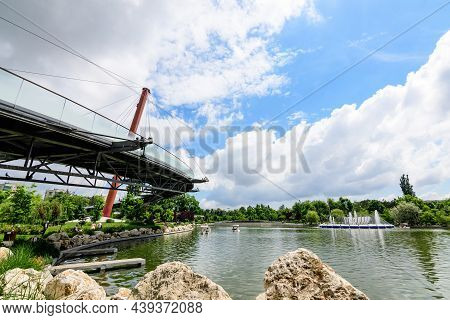 Landscape With The Modern Red Metallic Bridge, Lake And Vivid Green Trees In Drumul Taberei Park (pa