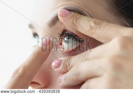 Young Woman Inserting Contact Lenses Into Her Eye With Finger Closeup. Correction Of Myopia Concept