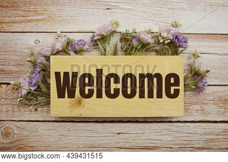 Welcome Sign With Flowers Frame Decprate On Wooden Background