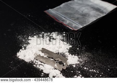 Razor Blade On Drug Powder,cocaine Bag On Reflection Black Background.copy Space.