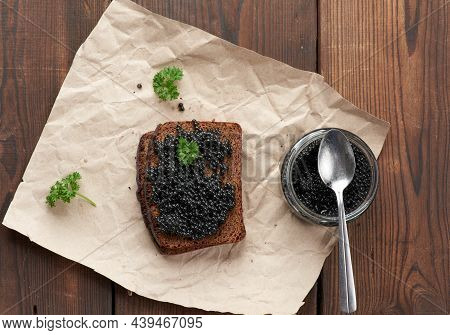 Paddlefish Caviar, A Slice Of Bread And A Jar On A Piece Of Brown Paper, Top View
