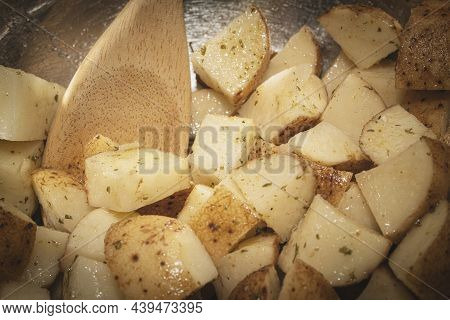 Mixing Potaoes For Roasting With A Wooden Spoon.