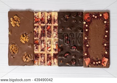 Different Kinds Fof Chocolate Bars Laying Down In A Row On Wooden White Background. Dark One, Milk A