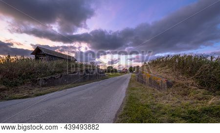 Road Passage Through Dike At Sunset Under Beautiful Clouded Sky. Usquert, Groningen, Netherlands