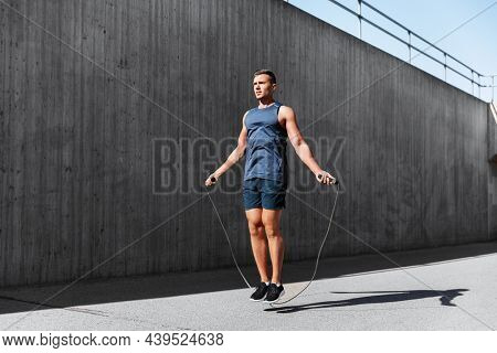 fitness, sport and exercising concept - man skipping with jump rope outdoors