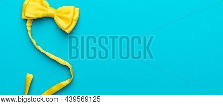 Top View Photo Of Yellow Satin Bow Tie Over Turquoise Blue Background With Copy Space. Minimalist Fl