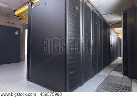 Data center with multiple rows of fully operational server racks. modern cloud computing technology concept.