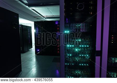 Data center with multiple rows of fully operational server racks. modern cloud computing technology concept.