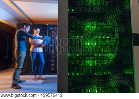 Diverse male and female engineers using laptop in computer server room. database server management and maintenance concept
