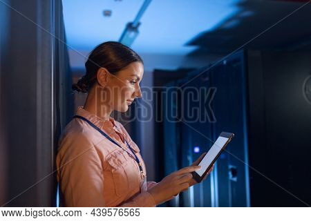 Caucasian female engineer using digital tablet in computer server room. database server management and maintenance concept