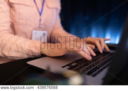 Mid section of woman using laptop in computer server room. database server management and maintenance concept