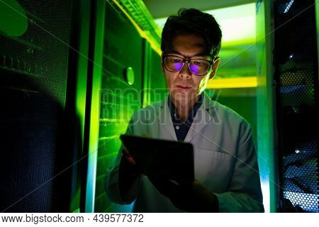 Asian male engineer wearing an apron using digital tablet in computer server room. database server management and maintenance concept