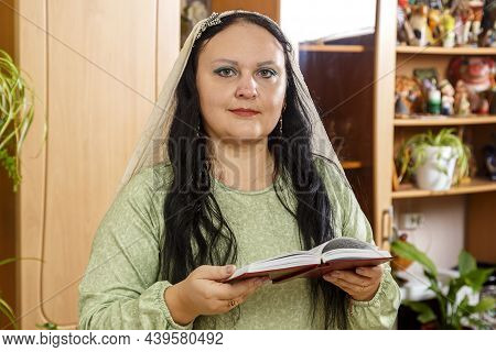 A Jewish Woman In A Cape On Her Head Reads The Kabbalat Shabbat Prayer From The Siddur.