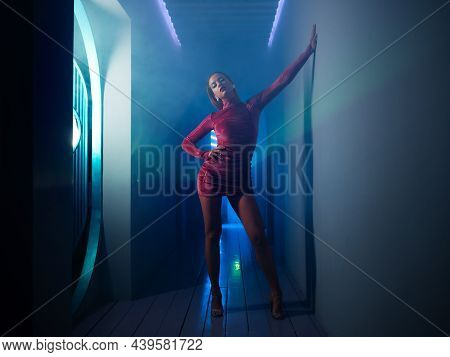 A Fashionable Photo Shoot With Tinted Blue, A Young Beautiful Model In A Scarlet Dress, In A Mysteri