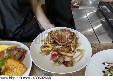 Cooked Bacon On Toast With Maple Syrup And Strawberries Served On A Large White Plate For Breakfast