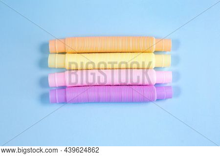 Multicolored Bright Tubes On Blue Background. Anti-stress Sensory Figet Plastic Toy.