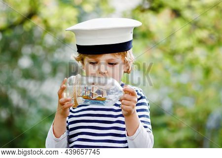 Happy Little Kid Boy In Sailor Capitain Hat And Uniform Playing With Sailor Boat Ship. Smiling Presc