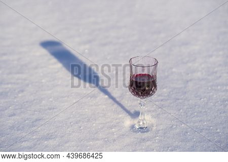 Homemade Tincture Of Red Cherry In A Wine Crystal Glass On A Snow And White Background