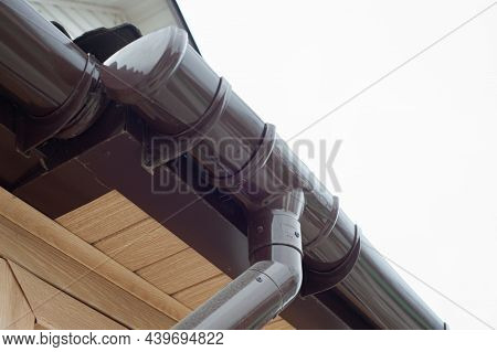 Gutter With Downpipe On The Roof Of A House.