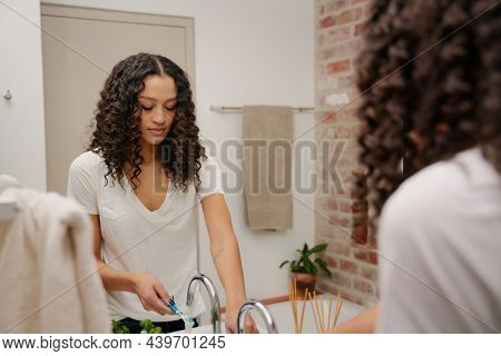 Mirror Reflection Of A Young African American Woman About To Brush Her Teeth With A Toothbrush In Th
