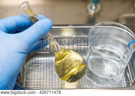 Scientist In Blue Rubber Puts A Yellow Solution In The Flask And Beaker For Dissolving Or Extraction