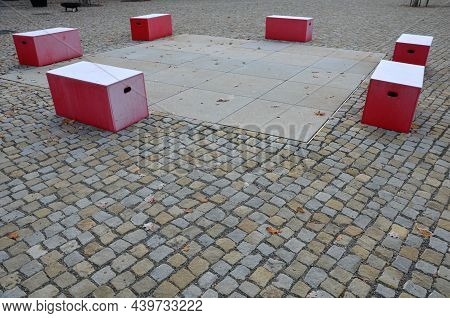 Red Plastic Benches In The Shape Of Blocks With Handles. The Square Is Paved With Granite Cubes. San
