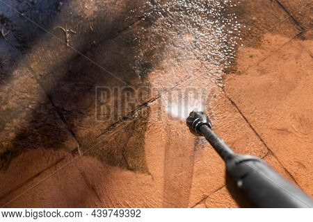Cleaning Dirty Backyard Paving Tiles With Pressure Washer Cleaner.