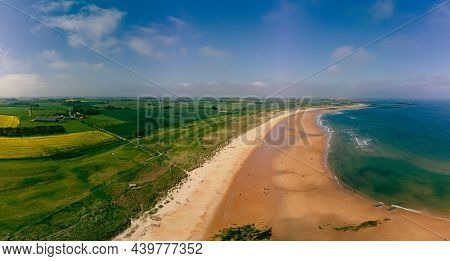 Embleton Bay and Burn with sandy beach with the ruins of Dunstanburgh Castle