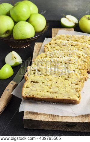 Sliced Apple And Coconut Oaf Cake On Wooden Cutting Board On Dark Background