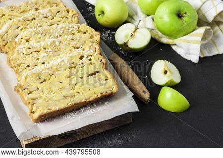Sliced Apple And Coconut Oaf Cake On Wooden Cutting Board On Dark Background
