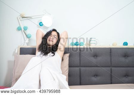 Asian Young Glasses Woman Stretches Oneself On Her Bed In The Morning.