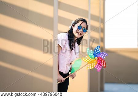 Asian Woman Posts And Play Windmill Toy Colourful Rainbow Colour On The Building Rooftop In Sunset T