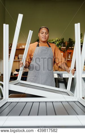 Young Adult African American Woman Starting Workday In Modern Cafe Preparing Tables Turning Over And