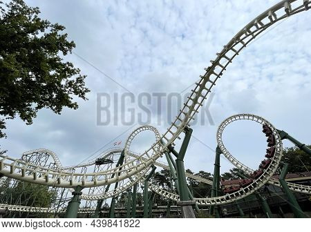 Two Rollercoasters Next To A Lake In A Themepark