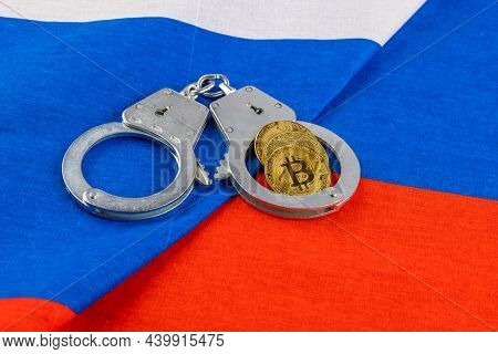 Roll Of Russian Paper Rubles Currency And Bitcoin Shiner Chained With Handcuffs On Russian Flag Back