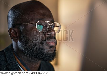 Close-up Of African Young Businessman In Eyeglasses Working On Computer Till Late Night