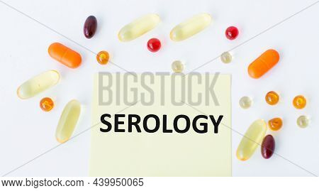 A Card With Text Serology On A White Background Next To Scattered Colored Pills, Medical Concept