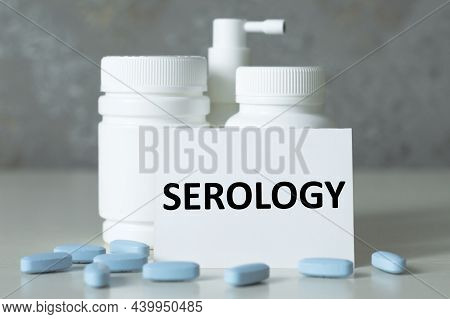 A Card With Text Serology On The Table Next To Medicine Jars, Pills, Medical Concept
