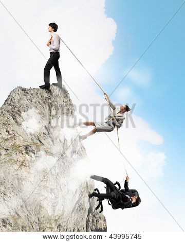 Imagem de três empresários puxando a corda no topo da montanha