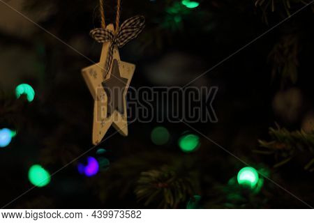Ornament Star Hanging On Fir With Christmas Lights In The Background
