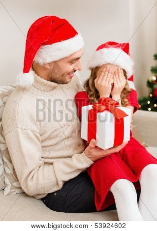 family, christmas, x-mas, winter, happiness and people concept - smiling daughter with closed eyes waiting for a present from fathe